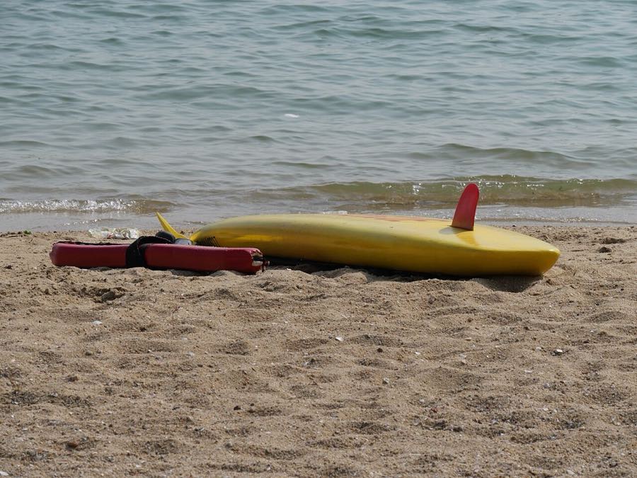 Yellow surfboard lying on the sand